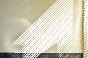 Abstract of morning light and shadow on tiled wall through window blind shutter 